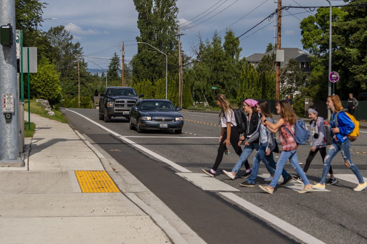 group of youth walking in crosswalk as cars wait